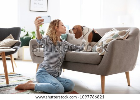 Young woman taking selfie with her dog at home