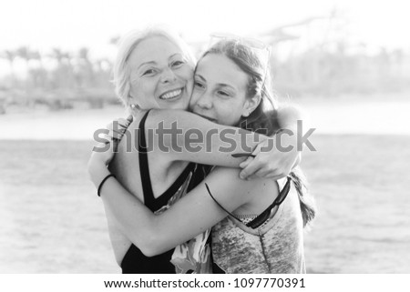 Cute pretty teen daughter with mature mother hugging in nature at sunset.monochrome, black and white photo.