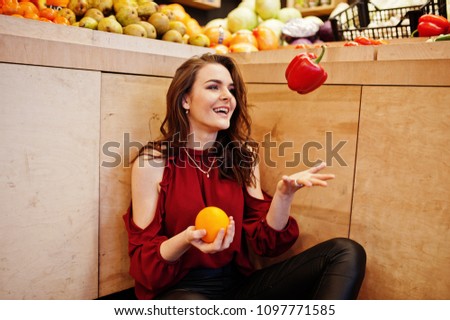 Girl in red throw peppers on fruits store.
