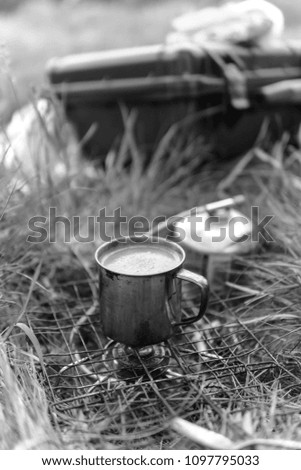 Small camping gas stove and small pot. coffee cup in the morning. selective focus. vertical photo, black and white bw