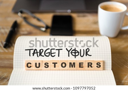 Closeup on notebook over wood table background, focus on wooden blocks with letters making Boost your income text. Concept image with laptop, glasses, pen and mobile phone in defocused background