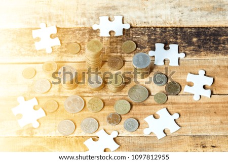 piece of blank jigsaw puzzle and coins on wooden table