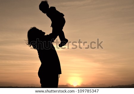 silhouette of mommy and small girl on the beach at dusk.