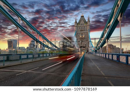 Red double decker bus crossing the Tower Bridge in London during unset time, United Kingdom