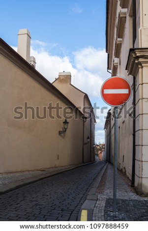 Narrow street and a do not enter traffic sign. Street lined by the houses of the old city in Prague, Czech republic. Blue sky with white clouds.