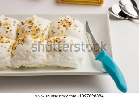 Portioned Traditional Turkish ice cream Maras in plate with a knife.A taste more than a hundred and fifty years in Turkey.Elastic texture and you have to chew it.
