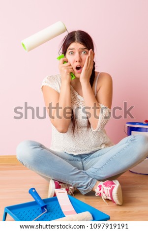 Image of young woman with paint roller sitting on floor