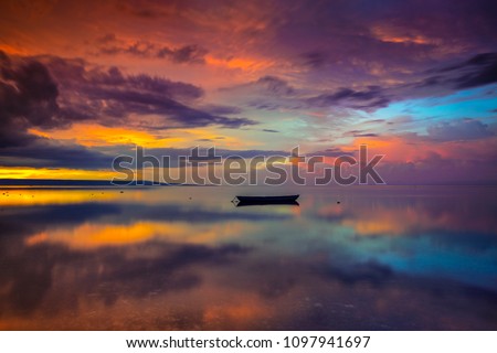 A boat on a calm beach with a surreal sunset at Walakiri Beach, East Sumba, Indonesia Royalty-Free Stock Photo #1097941697