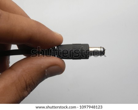 Hand of man holding black color male connector of power plug adapter on white background