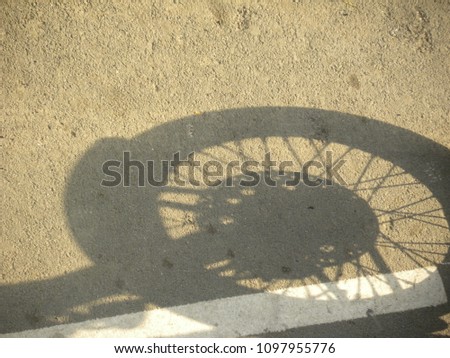 Shadow of front wheel of motorcycle parked on the road