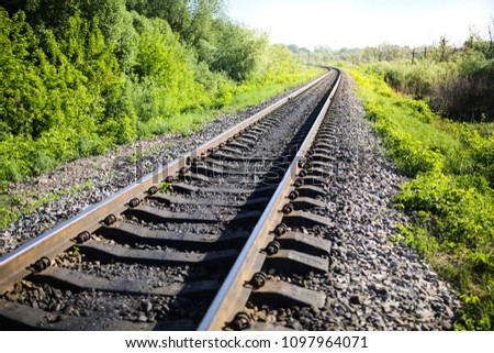 Rail tracks in the green field. Railway transport industry. Empty road on summer day. Travel lifestyle motivation photo.