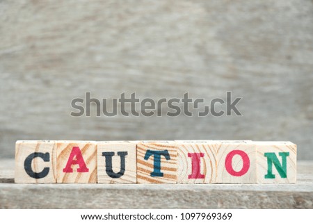Letter block in word caution on wood background