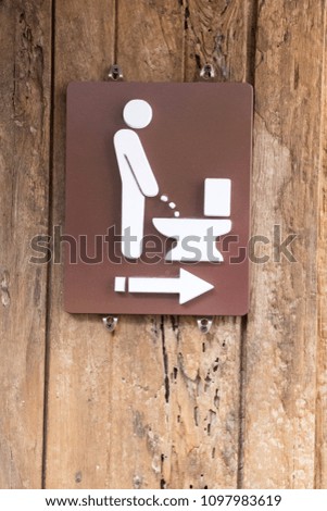 Male toilet sign on brown wood wall.