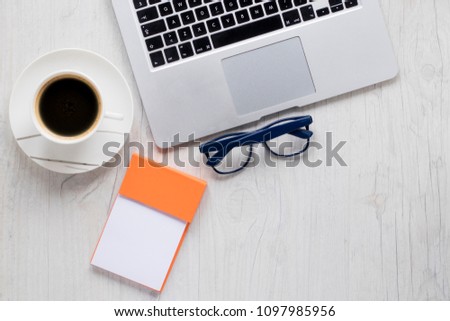 coffee cup ,laptop, glasses eyes and note on wood table