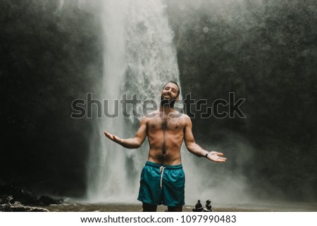Young handsome tourist visiting the nungnung waterfall in the bali island, indonesia. Having fun in the wild nature. Lifestyle. Travel photography.