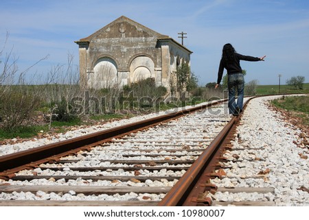 Young woman walking on the railway of an abandoned train station.