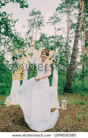 Beautiful woman in a wedding dress on a photozone decorated with fresh flowers, posing and portrait.