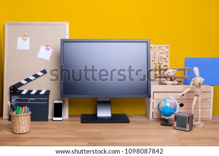 Cozy designed comfortable workplace with PC monitor and stationeries placed on wooden table for freelancer working at home office yellow wall concept