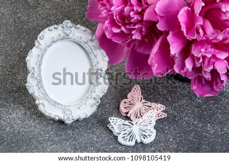 Pink peony, shabby frame and butterflies close up on gray textured background. Texture of concrete and copy space for text