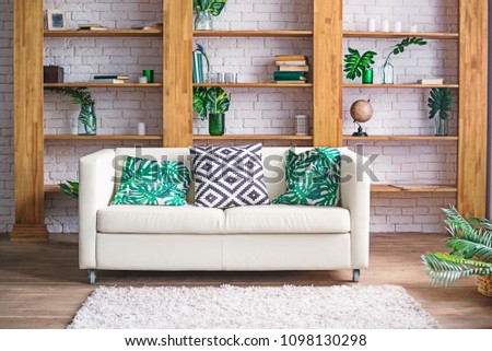 Cozy light room with plants, white sofa and stylish furniture in scandinavian style. Living room interior concept. Selective focus. Space for text.
