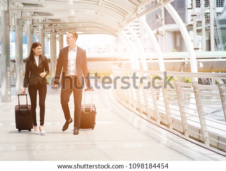Business people walking with luggage at  airport. Man and woman business suit vacation happiness trip.