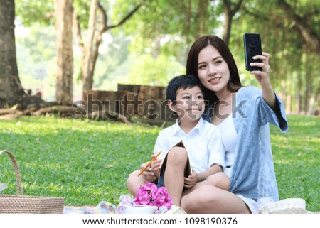 Mother and her son selfie picture while sitting and family picnic in a green park for vacation day