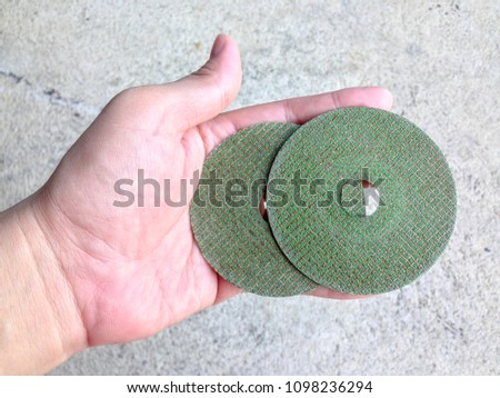 Close up green grinding wheel on my hand cement background.