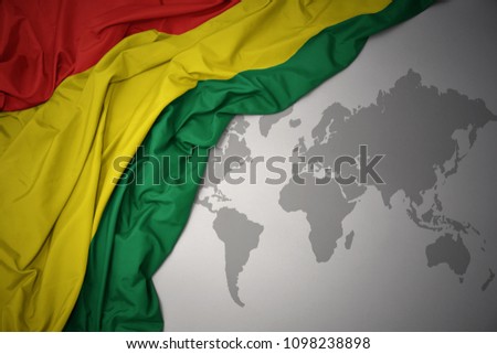 waving colorful national flag of bolivia on a gray world map background.