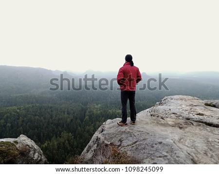 Man tourist hiker or trail runner looking at inspirational rocky  landscape in high mountains. Male runner enjoying view on rocky top of mountain