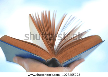 Close-up of hand holding old books opened selective focus and with a very shallow depth of field