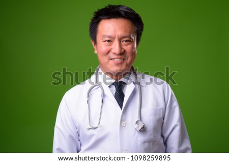 Mature Japanese man doctor against green background