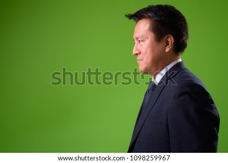 Mature Japanese businessman against green background