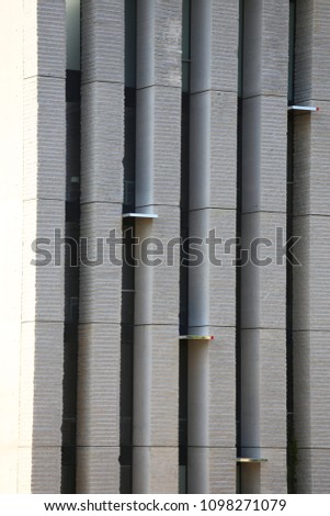 Abstract outdoor view of a grey concrete wall of a high modern building. Vertical lines and stripped textured surface. Architecural image with rough geometric elements. Graphic urban picture. 