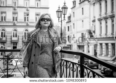 A woman of plus size, American or European appearance walks in the city enjoying life. A young lady with excess weight, xxl size at the center of the city. Natural beauty