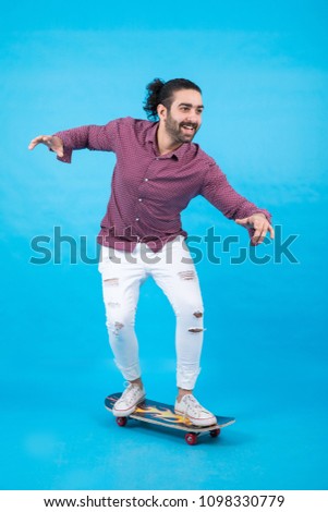 Active man wearing a casual outfit, ride his skateboard and enjoying his time, standing on a blue background