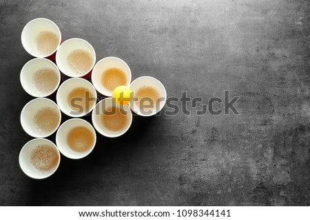 Cups and ball for beer pong on table, top view