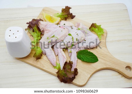 4 fresh chicken wings laid on wooden chopping board, vegetable color, side by side, on white background