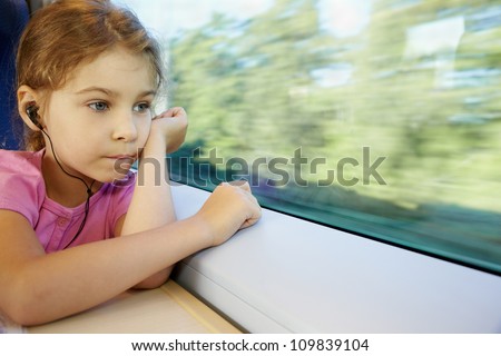 Girl listens to music, sitting by window of moving speed train