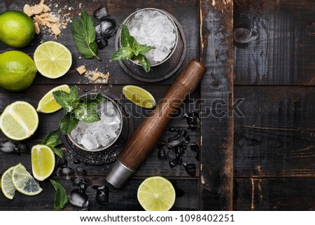 Mojito cocktail with lime, mint and crushed ice on dark vintage wooden background. Top view with copy space