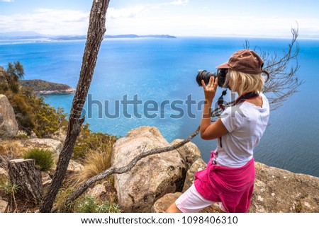 Nature travel photographer woman taking pictures on a spectacular cliff during the trek Fluted Cape Within the South Bruny National Park Bruny Island, Tasmania Australia.