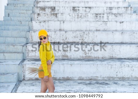 Portrait of beautiful asian woman in yellow cloths,Hipsters girl wear yellow hat on stair for take a picture,Thailand people in yellow tone style