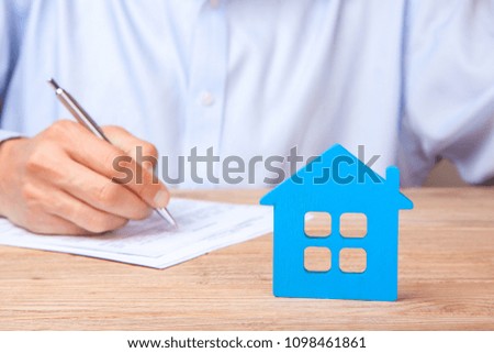 Concept home insurance, rent or purchase. Blue house and Man signs contract in the background