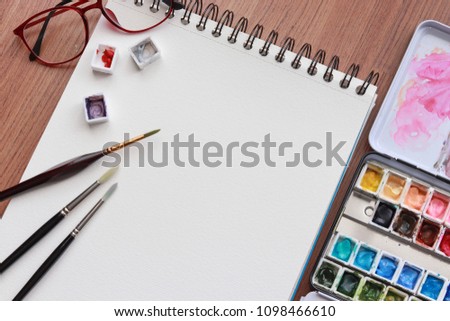 Paint accessories and watercolor And Blank Book on Wooden Table. (workplace mock up,Copy Space,Isolated, White Copy space,Color Copy space, Blank Copy Space, Wood Copy Space.)