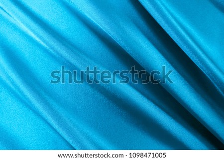 Beautiful smooth elegant wavy in sky blue color satin silk luxury cloth fabric texture, abstract background design. Copy space