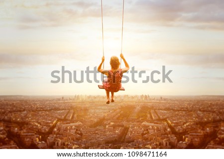 happiness and freedom concept, happy romantic beautiful young girl on the swing above the city landscape, cityscape at sunset, dream, joy and inspiration, inspiring life  Royalty-Free Stock Photo #1098471164