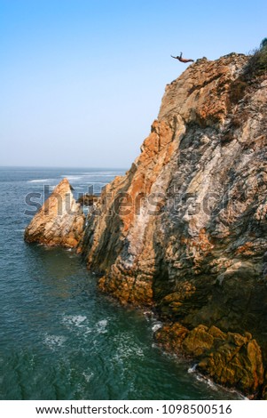 Cliff diver jumping from the rocky hill to the sea in Acapulco, Mexico.  Royalty-Free Stock Photo #1098500516