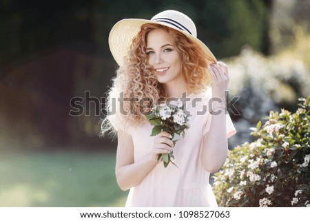 beautiful young woman in hat in blooming garden