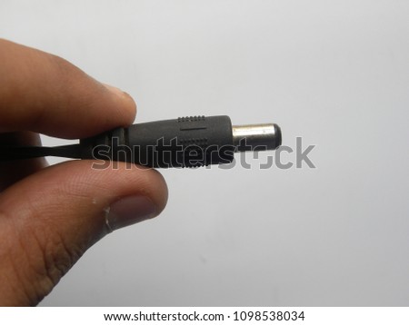 Hand of man holding black color male jack of power plug adapter on white background