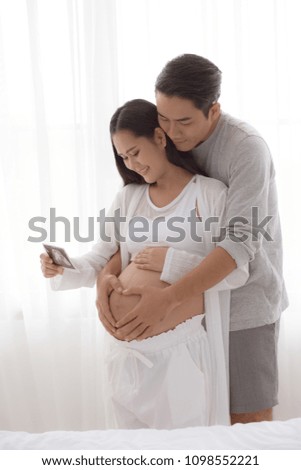 Pregnant women with her husband feeling happy when see ultrasound photo.