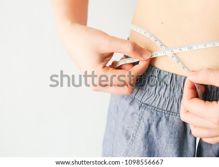 Close up hands measuring waist with a tape. Fit and healthy woma